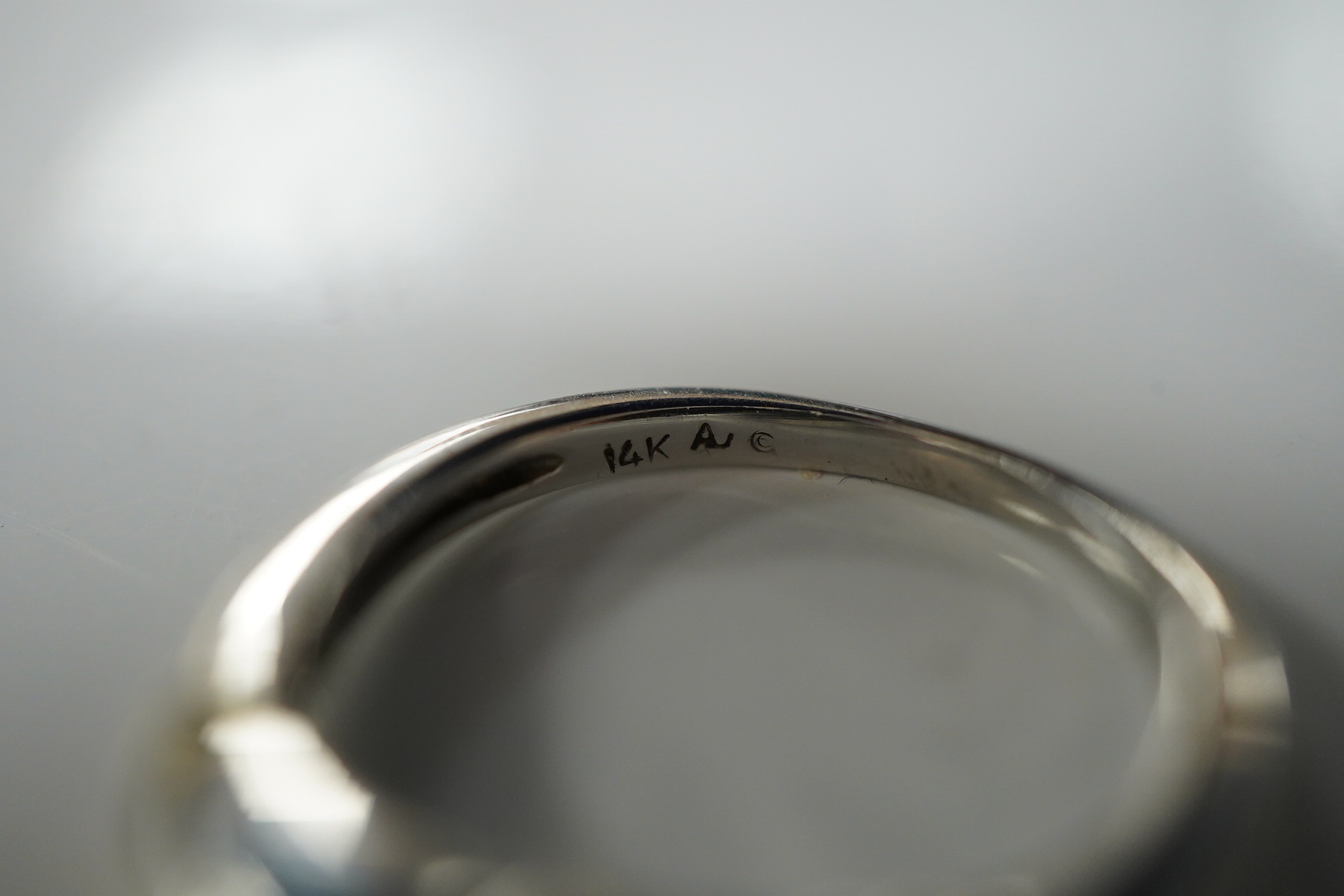 A diamond ring, claw-set with a brilliant-cut diamond weighing approximately 0.30 carats, to shoulders channel-set with smaller brilliant-cut diamonds, mounted in white gold, size R, stamped 14K, gross weight approximate